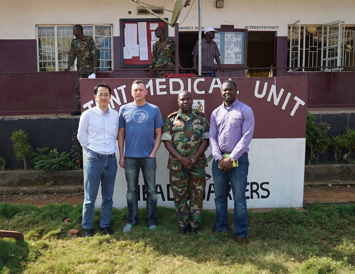 Photo: UW–Madison’s Yoshihiro Kawaoka, Peter Halfmann and Alhaji Njai stand outside of a military hospital with Foday Sahr