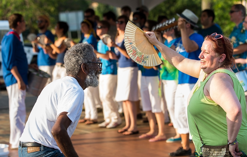 Photo: Community members Luis Fis, and Catherine King dance to a performance by the Handphibians, a Brazilian percussion group