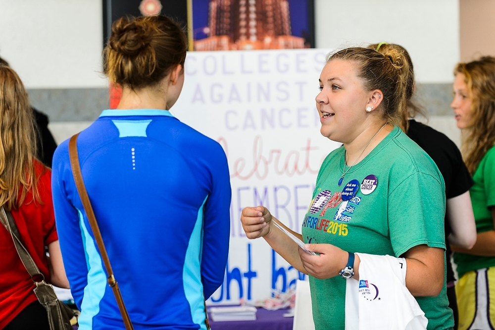 Photo: A member of the Colleges Against Cancer, at right, speaks with students