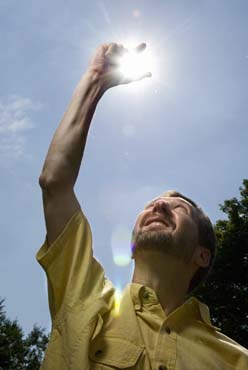 Photo of Jim Winkle holding his hand up to the sky as if to grasp the sun.