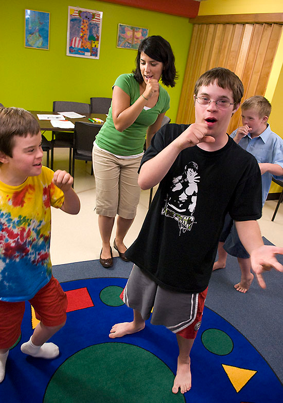 Three children with Down syndrome sing along with a speech-language pathology graduate student.