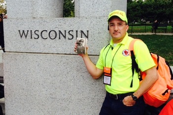 Photo: Mike Garren holding picture of father in uniform at WWII Memorial