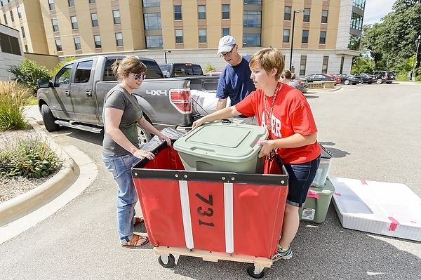 Photo: volunteer helping student move in to residence hall