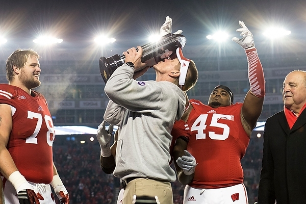 Photo: Coach Gary Andersen kisses the Big Ten West Division Trophy as Wisconsin players celebrate their team’s victory