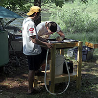 Photo of student in the woods performing surgery on a fish.