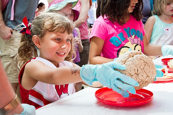 Thanks to a booth hosted by UW medical students, Gianna Carlino happily dons gloves and holds a human brain.