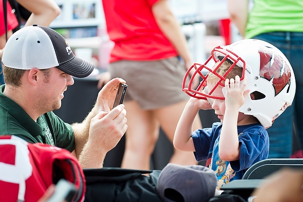Future Badger quarterback? A father photographs his son as he tries on a UW helmet.