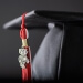 Closeup of a black cap from cap and gown with red and white tassel with small Bucky Badger charm