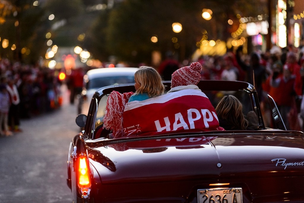Huddling under a banner (full disclosure: Happy Homecoming), children ride in the back of a vintage car and wave to thousands of spectators lining State Street during the annual Homecoming Parade.