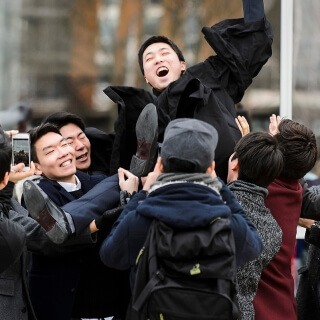 New graduate Chunghwan Oh is hoisted high by friends.