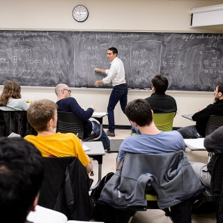 Chalky hand meets blackboard as Daniel Erman, assistant professor in mathematics, substitute teaches a graduate-level, abstract algebra class in Van Vleck Hall at the University of Wisconsin-Madison on Feb. 3, 2016. Erman, who is on paternity leave for part of the Spring 2016 semester, is one of twelve 2016 Distinguished Teaching Award recipients. (Photo by Jeff Miller/UW-Madison)