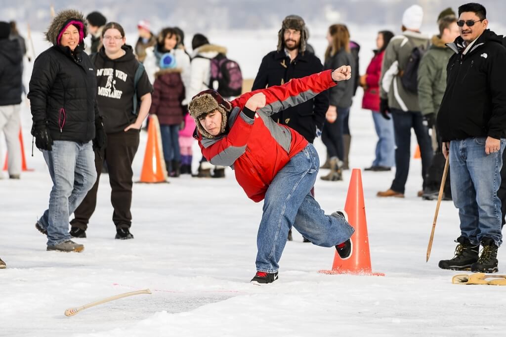 Participants take part in an Ojibwa Winter Games event on a frozen Lake Mendota at the University of Wisconsin-Madison on Feb. 5, 2016. The games included snow snake (shown), hoop and spear, and atlatl, where participants propel an arrow with a hooked handle. The Ojibwa Winter Games celebrate and sustain traditional winter sports, and inspire children to get out and exercise during winter. This year, a group of folklore students in the UW Scandinavian Studies Program partnered with educators in Lac du Flambeau to bring the games to UW-Madison. (Photo by Bryce Richter / UW-Madison)