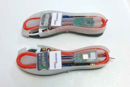 Upside-down shoe soles with an energy harvester, battery and electronics suite integrated into each sole. The harvester directly powers the electronics suite.