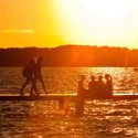 As the sun sets, UW-Madison students and visitors enjoy a cool summer evening on a Lake Mendota pier in July 2013.