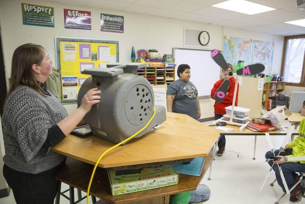 Photo: Lisa Andresen, left, cranks up the “wind” to turn a classroom-scale turbine as part of lessons she created after attending courses for educators at the Wisconsin Energy Institute.