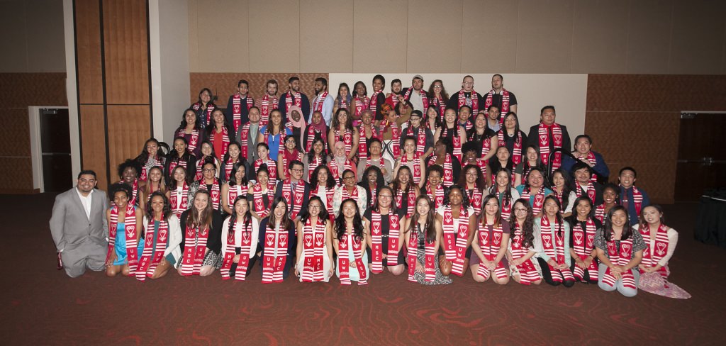 Wearing red and white kente cloth stoles embroidered with meaning, graduates pose with their Multicultural Student Center family and friends.