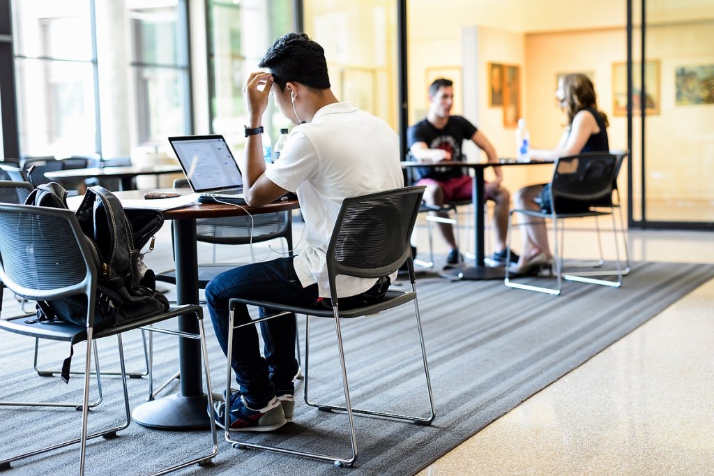 A student studies in the foreground at Morgridge Commons in the Education Building. In the background, Julie Stamm, associate lecturer of kinesiology in the School of Education, meets with undergraduate student Joe Erbstoesser.