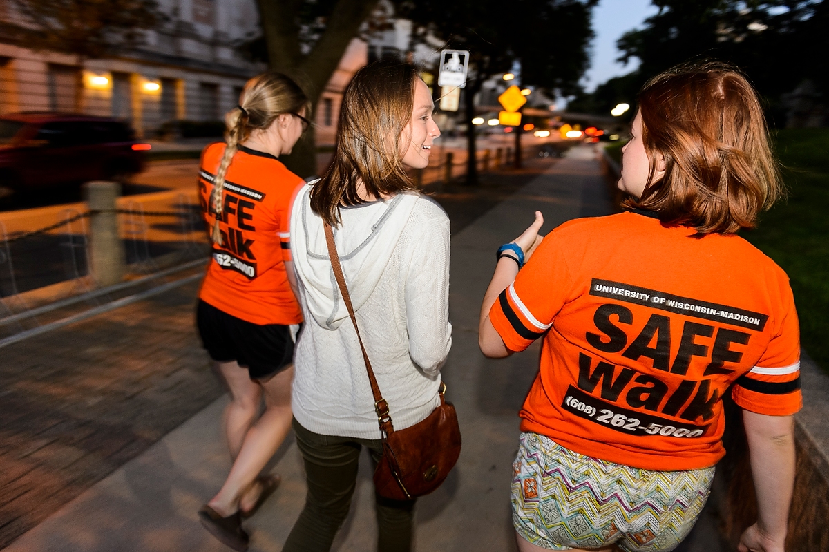 SAFEwalk staff members escort a UW-Madison student. SAFEwalk is a free campus service that provides trained, two-person walking escorts throughout the main campus.