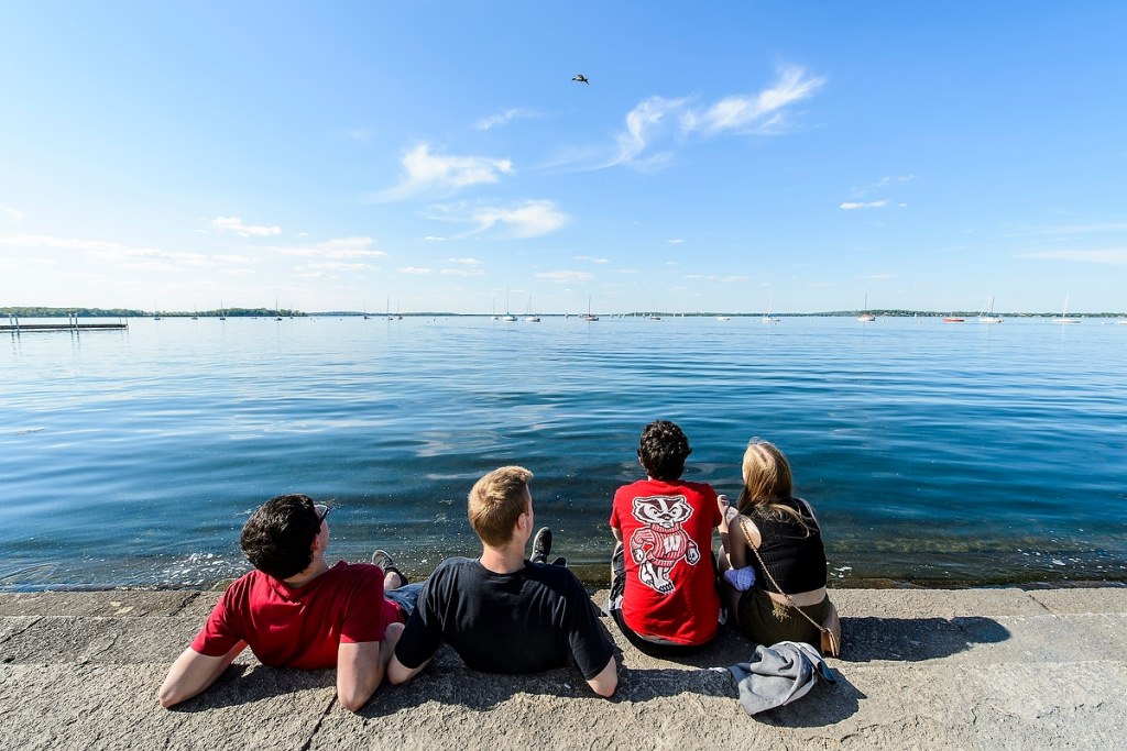 Photo: Students sitting along lake