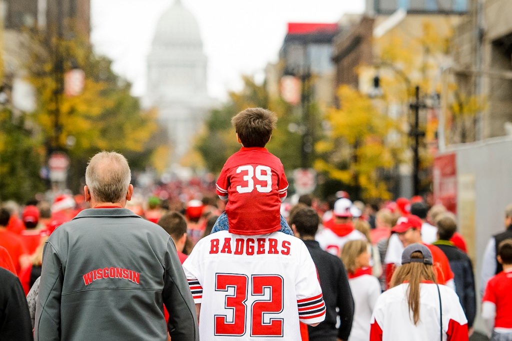 Photo: Child in Badger jersey riding on adult's shoulders