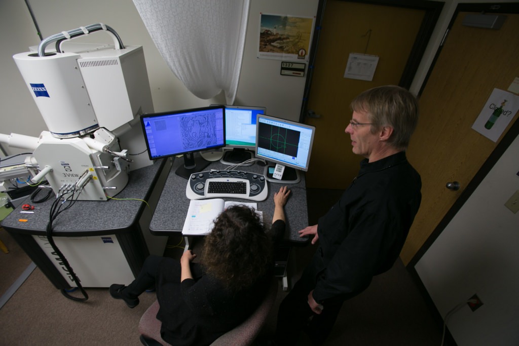 Drs. Cirelli, foreground, and Tononi, right, study an image of a mouse brain taken by a scanning electron microscope, left. Thousands of these images were analyzed for the study published this week in the journal Science. 
