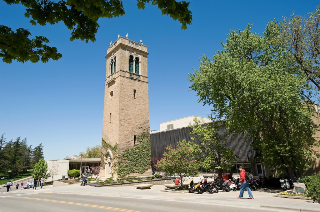 Trees and pedestrians frame a view of the Carillon Tower in front of the Sewell Social Sciences Building.