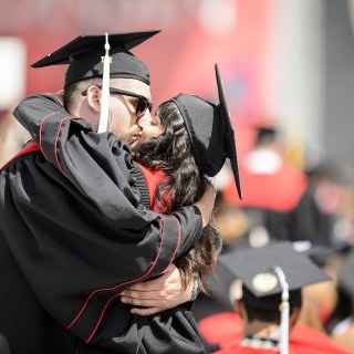 Graduates Jacob Barth (left) and Shanti Varma-Lenz (right) celebrate with a kiss.