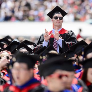 A graduate holds up his fingers to form the iconic W.