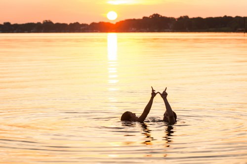 Having stayed up all night, undergraduates Loran Zweifelhofer and Willis Perley form a W hand sign as they greet the morning sunrise over Lake Mendota with a swim from the Goodspeed Family Pier near the Memorial Union Terrace at the University of Wisconsin–Madison on June 19, 2015. The two friends met during their freshman year and are now seniors. (Photo by Jeff Miller/UW-Madison)