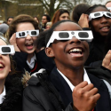 Students watch a solar eclipse through solar glasses, which allow safe viewing of the sun.
