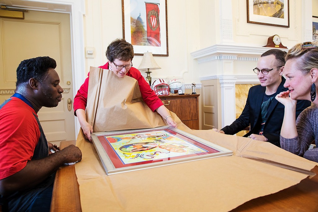 UW-Madison Chancellor Rebecca Blank receives a gift of artwork from alumnus and local artist Michael Ward, left, on Aug. 16.