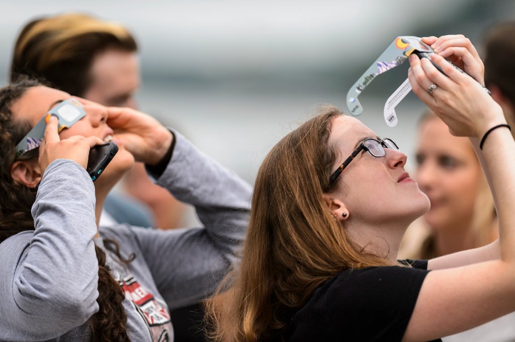 UW-Madison undergraduate Jennifer Glaser (left) and graduate student Eileen Lynch (right) wear solar-filtered eyeglasses to watch the moon as it passes orbit in front of the sun for a maximum 85-percent solar eclipse -- as seen from the Memorial Union Terrace at the University of Wisconsin-Madison -- on Aug. 21, 2017. A total-solar eclipse was visible, for the first time in almost 100 years, along a coast-to-coast path across the middle of the United States from Oregon to the Carolinas. (Photo by Jeff Miller / UW-Madison)