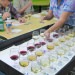 Volunteers distribute another flight of samples, each identified by number, at Wine is Wisconsin on the UW-Madison campus on Aug. 7, 2017. In the background, judges evaluate each entry’s “nose” and taste.