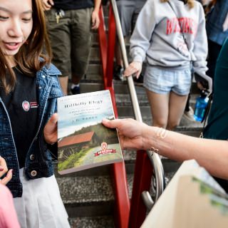Photo: Volunteer handing book to student