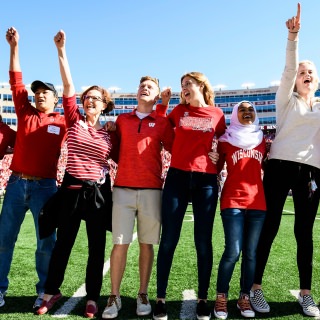 Wearing stripped shirt, Sarah Schutt, chief alumni officer and executive director of Wisconsin Alumni Association, sings "Varsity" with members of the homecoming committee during halftime of the UW Homecoming football game against the Maryland Terrapins at Camp Randall Stadium at the University of Wisconsin-Madison on Oct. 21, 2017. The Wisconsin Badgers won the game, 38-13. (Photo by Jeff Miller / UW-Madison)