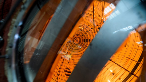 A view inside a fusion energy device known as the Big Red Ball. There are silver metal components in the foreground against an orange background that seems to glow with energy.