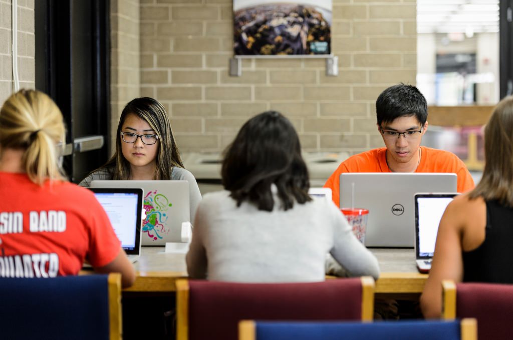 Photo: Students sitting at a table looking at laptop screens