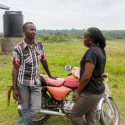 HAC program director Carolyne Ariokot and borrower Mike Nsubuga discuss logistics. Mike paid off the first motorcycle loan in February, 2017, and now owns this cycle.