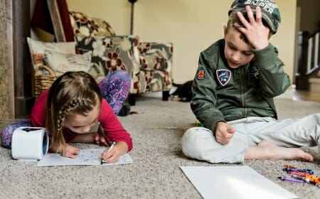 Photo of two siblings coloring.