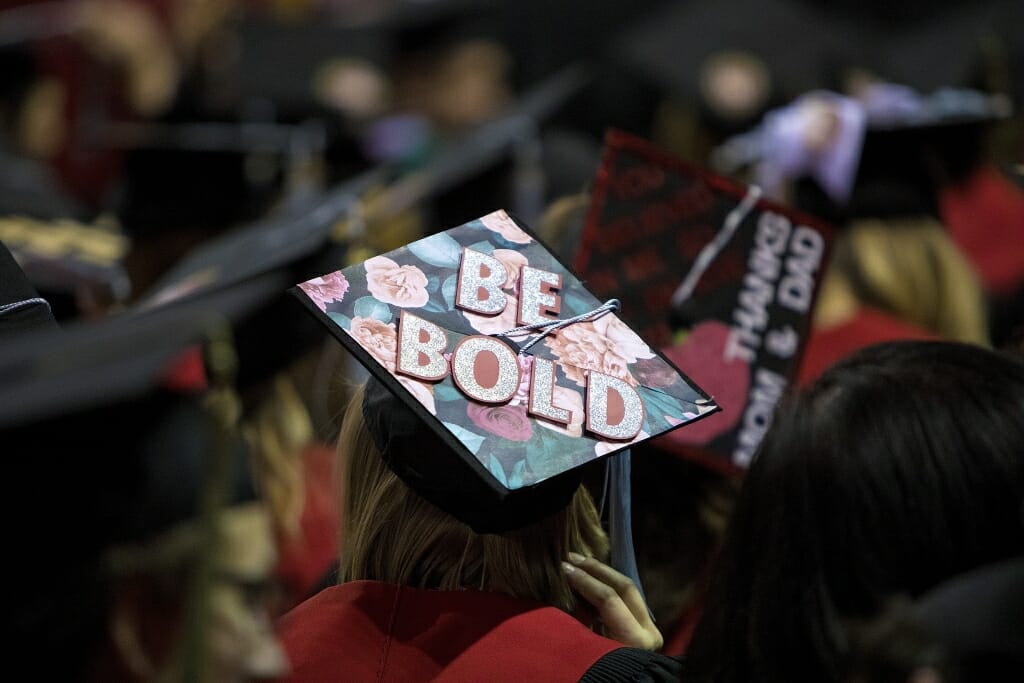 Photo of student wearing a mortarboard that says "Be bold."