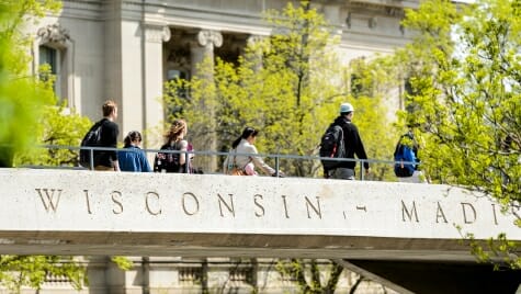 Photo: Students walking across pedestrian bridge that says