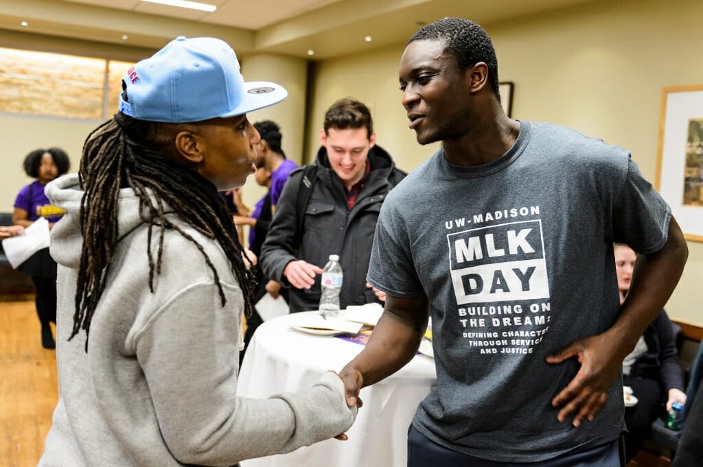 Undergraduate Paul Jackson II, a student athlete on the football team, shakes Waithe's hand.
