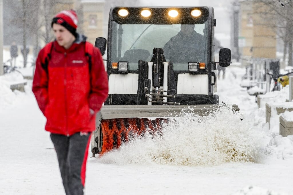 UW grounds crew members work to clear snow from the sidewalks on East Campus Mall.