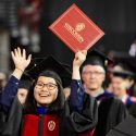 Photo: Doctoral graduate holding up hands with diploma cover