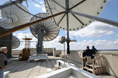 Large satellite dishes and other equipment cover the top of a building.