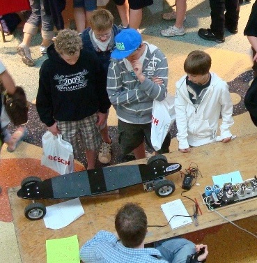 Photo: Students looking at a motorized skateboard
