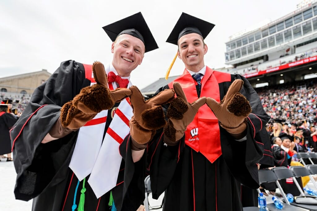 Photo of graduates Shane Hoffman, left, and Seth Van Krey, flashing the W sign while wearing badger mitts.