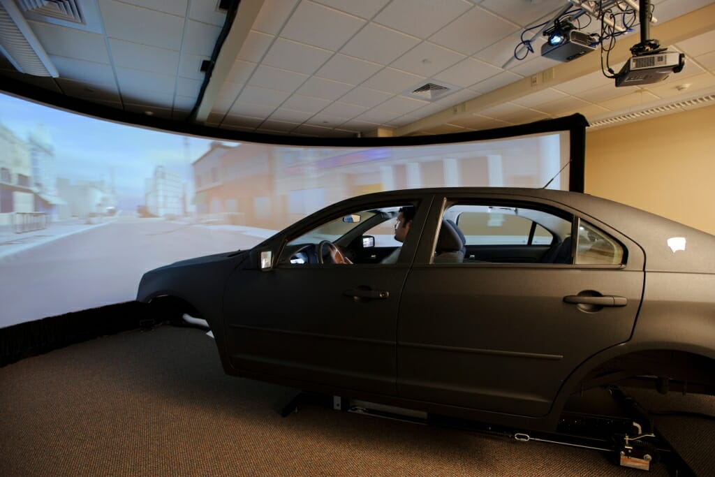 Photo: Man in car simulating driving in front of projection screen