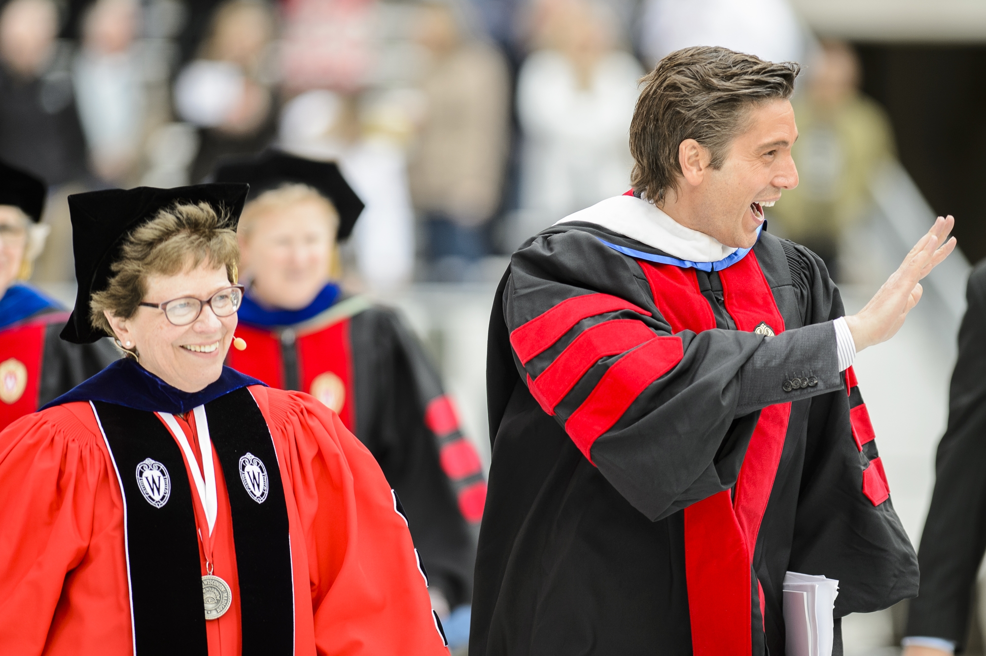 Photo of Photo of commencement speaker David Muir, an Emmy-winning journalist, and Chancellor Rebecca Blank walking among the graduates at Camp Randall Saturday.