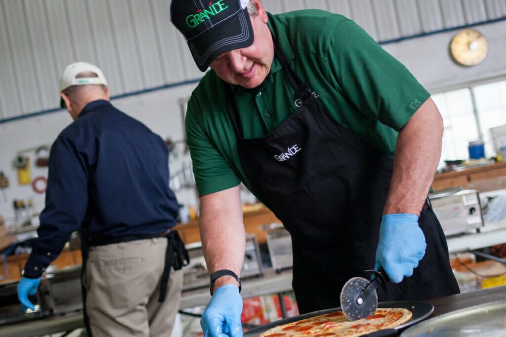 Photo: Man in apron slicing pizza